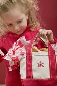 Kleines Mädchen hält Tasche mit Zuckerstangen und Plätzchen