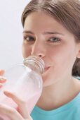 Young woman drinking strawberry milk out of bottle