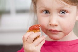 Kleines Mädchen hält Chicken Nugget mit Ketchup