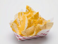 Nachos with cheese sauce in a paper dish