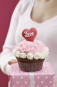Frau hält Cupcake und Geschenk zum Valentinstag