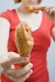 Frau isst frittierte Hähnchenkeulen