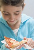Kleines Mädchen hält Stück Pizza