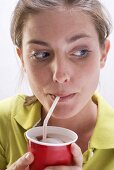 Young woman in green blouse drinking cola