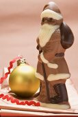 Weihnachtsmann aus Schokolade neben Christbaumkugel