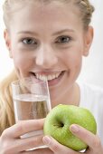 Woman holding apple and glass of water