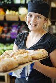 Baker with tray of bread rolls in supermarket (Sweden)
