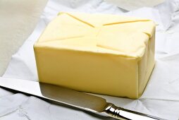 Block of butter on paper, knife beside it