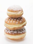 Three doughnuts dusted with icing sugar, stacked