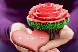 Hände halten Cupcake und Plätzchen zum Valentinstag