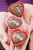 Hände halten Schokoladengebäck zum Valentinstag