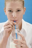 Young woman drinking milk from the bottle with a straw