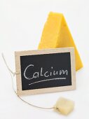Slate board with the word Calcium in front of piece of Cheddar
