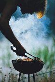 Young man barbecuing food at twilight