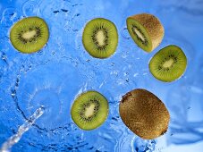 Stream of water running onto kiwi fruit and kiwi fruit slices