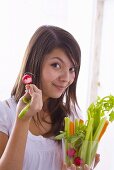 Girl holding raw vegetables and a bitten radish