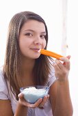 Girl eating a carrot with yoghurt dip