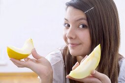 Girl holding two wedges of honeydew melon