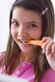Girl biting into a carrot