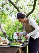 Frau zuckert Erdbeertorte am Buffet im Garten (Schweden)