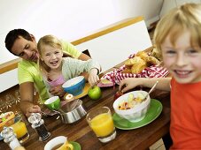 Vater, Tochter und Sohn sitzen am Frühstückstisch