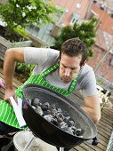 Mann bereitet den Grill auf dem Balkon vor