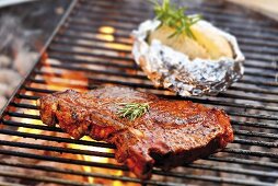 T-bone steak and baked potato on barbecue rack
