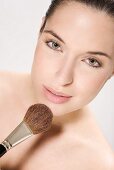 Young woman using make up brush, portrait