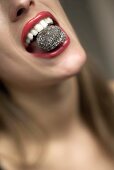 Frau mit einer Schokoladenpraline im Mund