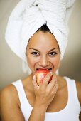 Woman in towel turban eating an apple