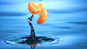 Mandarin orange segments falling into water