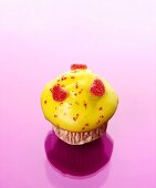 Muffin with yellow icing and sugared jelly hearts