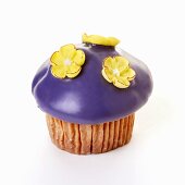 Muffin with purple icing and sugar flowers