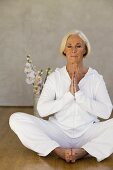 Senior woman with eyes closed in yoga position, smiling