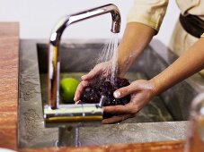 Woman washing grapes at kitchen sink, mid section