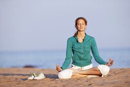 Junge Frau macht Yoga am Strand