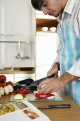 Young man cutting vegetables in kitchen, close-up