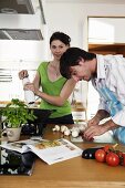 Young couple in kitchen, man cutting vegetables