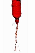 Red energy drink squirting out of bottle