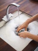 Woman washing crockery in sink