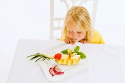 Girl sitting at table in front of plate of fruit