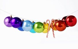 Shiny, coloured Christmas baubles & candy canes on washing line