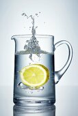 Lemon falling into jug of water