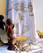 Engel aus Stein vor bedrucktem Tuch, goldene Flügel