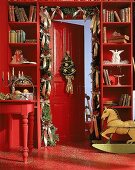 Rotgestrichene Tür, geschmückt mit Girlande, Schaukelpferd , Engel