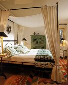 Bett mit Leinenhimmel, indischer grüner Schrank und passende Kissen