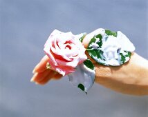 Rosenblüte mit Blättern in einer Hand, mit weißer Creme eingeschmiert