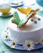 weiße Zitrus-Sandtorte, dekoriert mit bunten Keks-Schmetterlingen