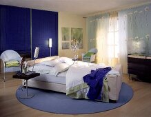 Schlafzimmer: Blaue Stäbchenrollos, weißes Bett, zartblaue Vorhänge