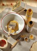 Malutensilien für Wandbemalung, Abtönfarbe gelb u. ocker und Pinsel